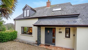 A two-story house with a dark roof, a small window, and a door. - 4 Bed in Tenby (oc-vv27177) (Manorbier)