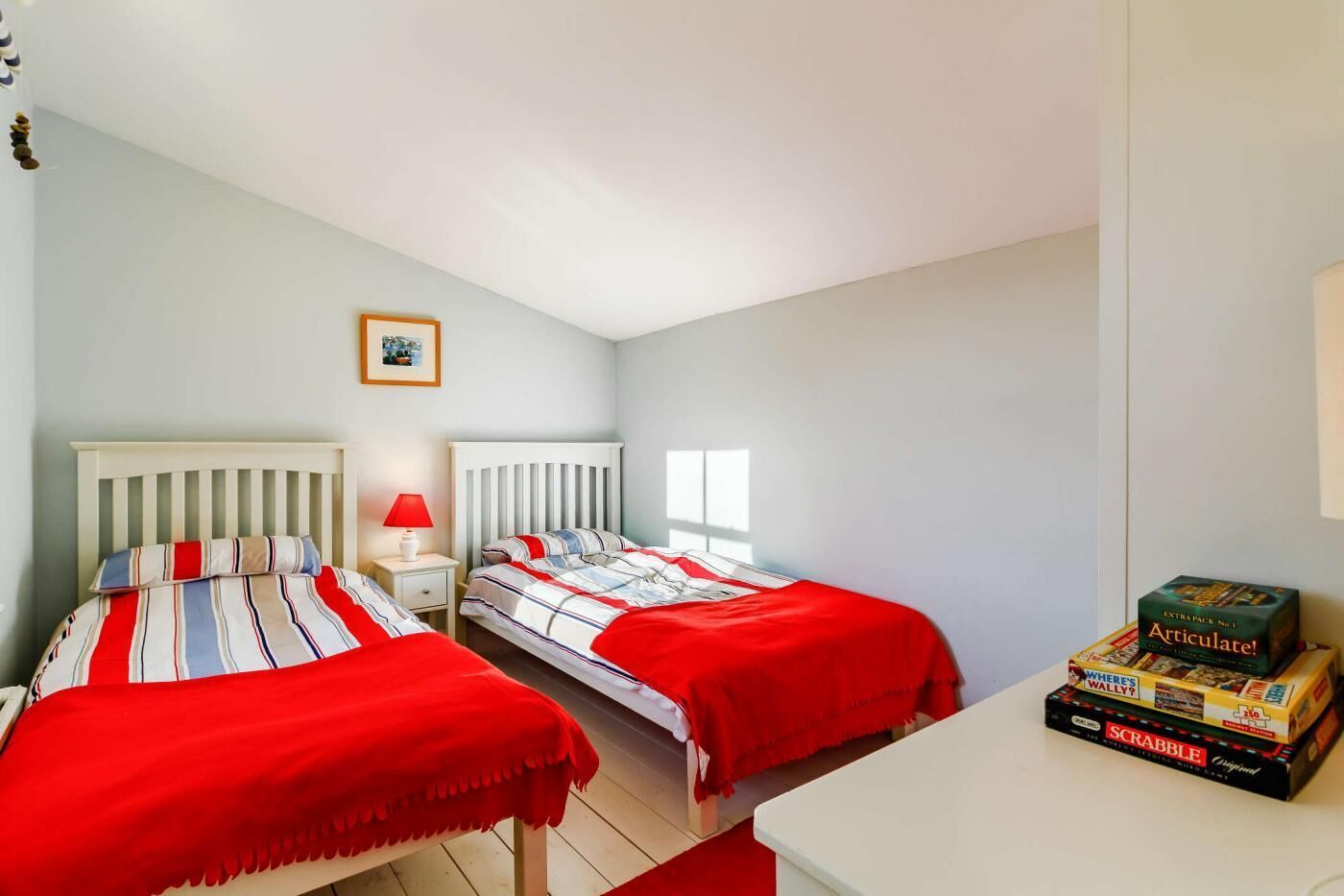 Una camera da letto con due letti, un comodino con una lampada e un tavolo con giochi da tavolo.