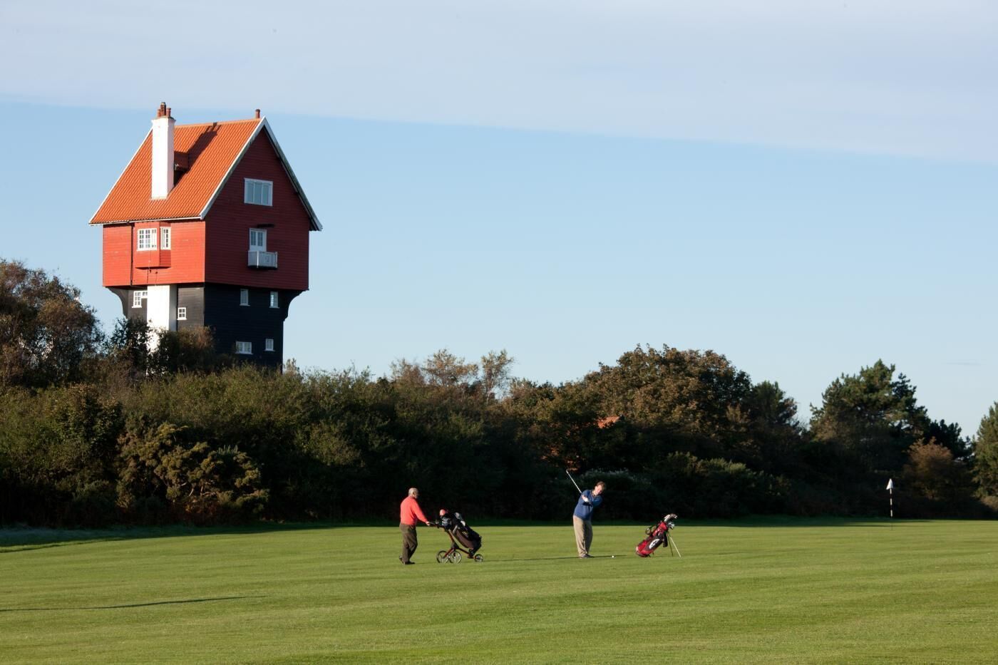 A golf course with a red house in the background.