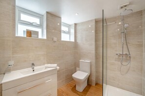 Une salle de bain moderne équipée d’une douche, de toilettes et d’un lavabo.