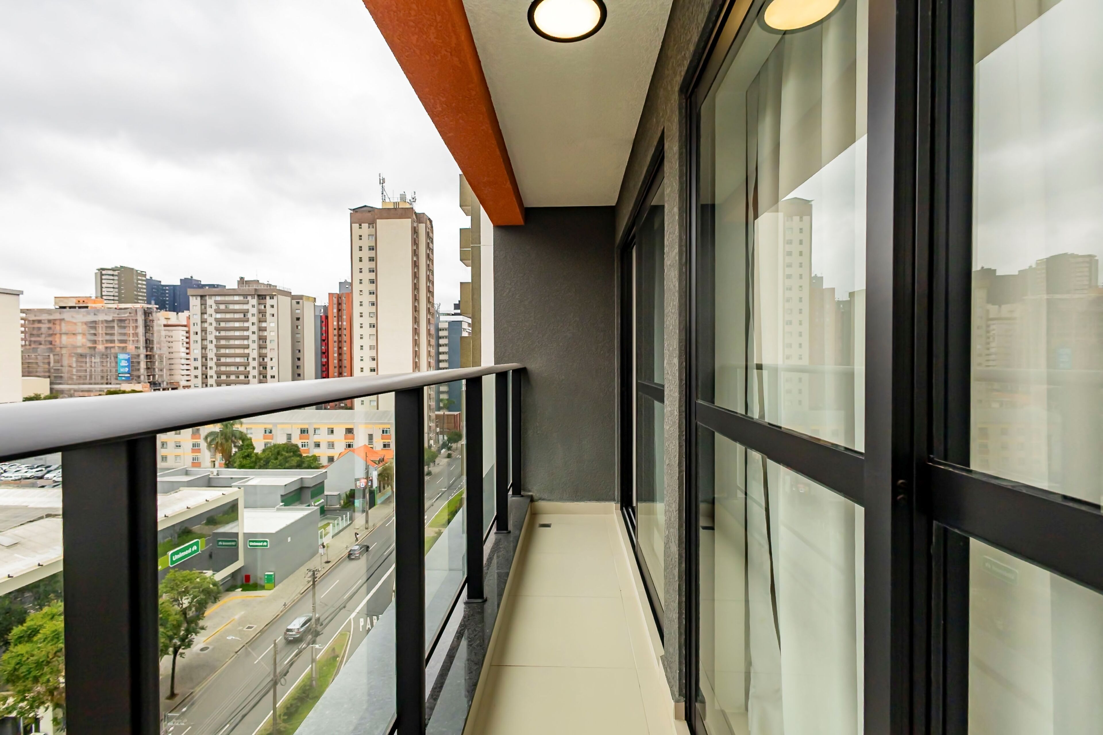 Un balcón con vista a la ciudad, una puerta de vidrio y barandilla de metal.