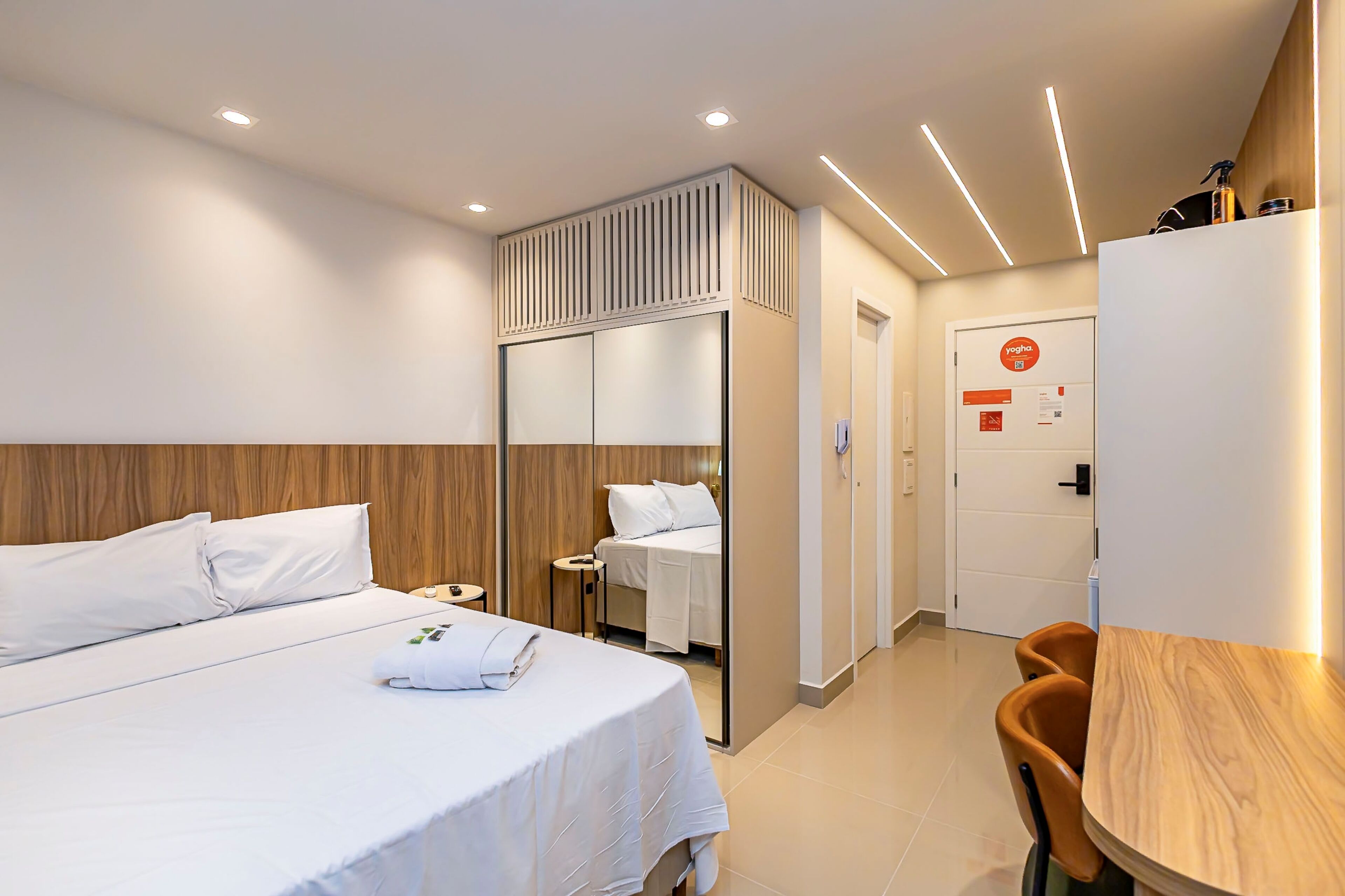 Una habitación de hotel con cama, escritorio, silla, armario y baño.