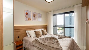 A modern hotel room with a large bed, a bedside table, a window with curtains, and artwork on the wall. - MUV Residence (Curitiba)