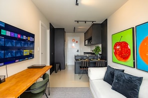 Ein modernes Wohnzimmer mit einem Holztisch, einem weißen Sofa und einer Küche im Hintergrund.