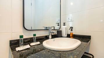 A bathroom with a white sink, a mirror, and toiletries on the counter.