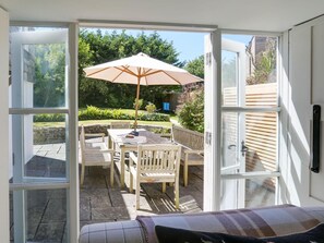 An open patio with a table and chairs, a large umbrella, and a view of a garden. - 4 Bed in Rock (oc-r27255) (Rock)