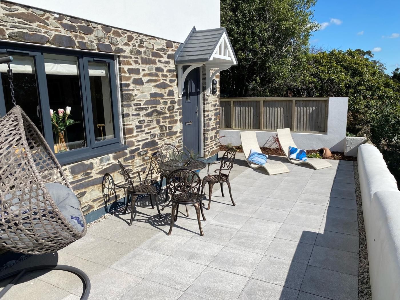 A patio with stone walls, a table with chairs, and lounge chairs.