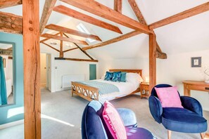 A bedroom with a wooden ceiling, a bed with blue and pink pillows, and a desk with a chair. - 1 Bed in Eye (oc-tch1) (Eye)