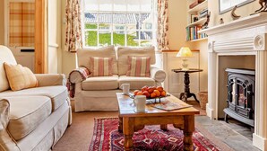 A cozy living room with a sofa, a coffee table with oranges, and a fireplace. - 2 Bed in Yoxford (oc-c27253) (Wickham Market)