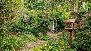 A garden pathway with a wooden birdhouse and a white bird feeder. - 2 Bed in Yoxford (oc-c27253) (Wickham Market)