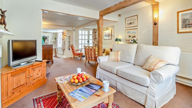 A cozy living room with a television, wooden furniture, a white sofa, and a dining table with fruits. - 2 Bed in Yoxford (oc-c27253) (Wickham Market)