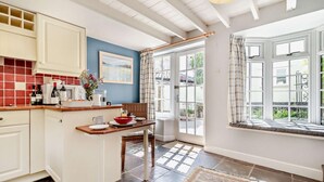 A kitchen with a dining area, a view through a glass door, and a patterned rug. - 1 Bed in Yoxford (oc-c27254) (Wickham Market)