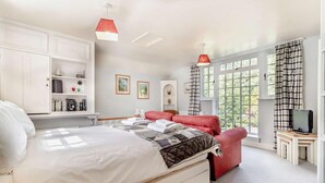 A bedroom with a large bed, a red chair, a TV, and a window with curtains. - 1 Bed in Yoxford (oc-c27254) (Wickham Market)