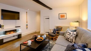 A modern living room with a fireplace, a sofa, a coffee table, and a television. - 2 Bed in Holt (oc-c27160) (Holt)