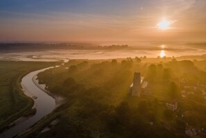 A river meandering through a landscape with a prominent tower-like structure and a few buildings, under a clear sky. - 3 Bed in Blythburgh (oc-h27263) (Blythburgh)