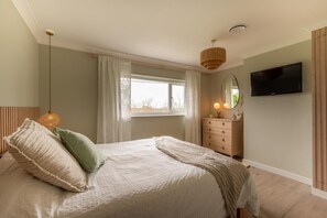 A bedroom with a bed, a dresser, a television, and a window with curtains. - 3 Bed in Blythburgh (oc-h27263) (Blythburgh)