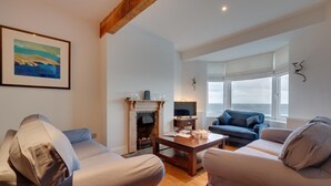 A living room with a fireplace, two sofas, a coffee table, and a television. - 4 Bed in Amroth (oc-g27016) (Amroth)