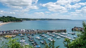 A marina with numerous boats docked, a pier with vehicles, and a beach in the background. - 4 Bed in Amroth (oc-g27016) (Amroth)