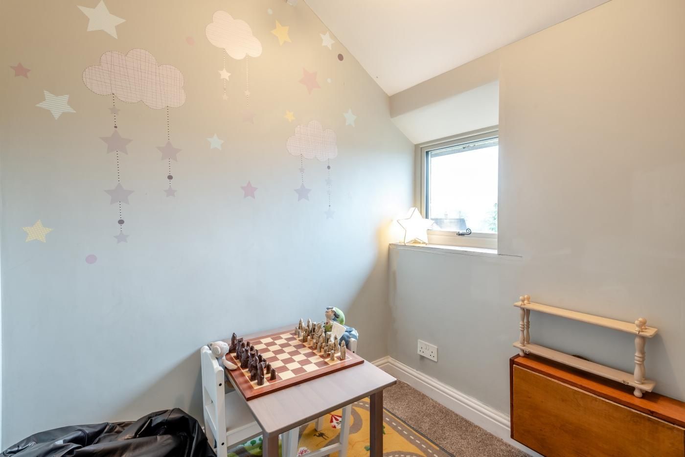 A child's playroom with a checkered floor, a wooden table, and a window with a view.