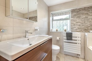 Ein modernes Badezimmer mit einem großen Waschbecken, einer Toilette und einem Fenster mit Blick.