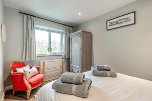Une chambre à coucher avec un lit, une chaise rouge, un radiateur et une armoire.