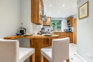 A modern kitchen with wooden cabinets, a breakfast setup, and a view of the outdoors. - 3 Bed in Baslow (oc-h27288) (Baslow)