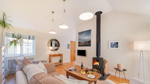 A cozy living room with a sofa, a coffee table with snacks, a fireplace, and a large window. - 3 Bed in Wilby (oc-slowlo) (Wilby)