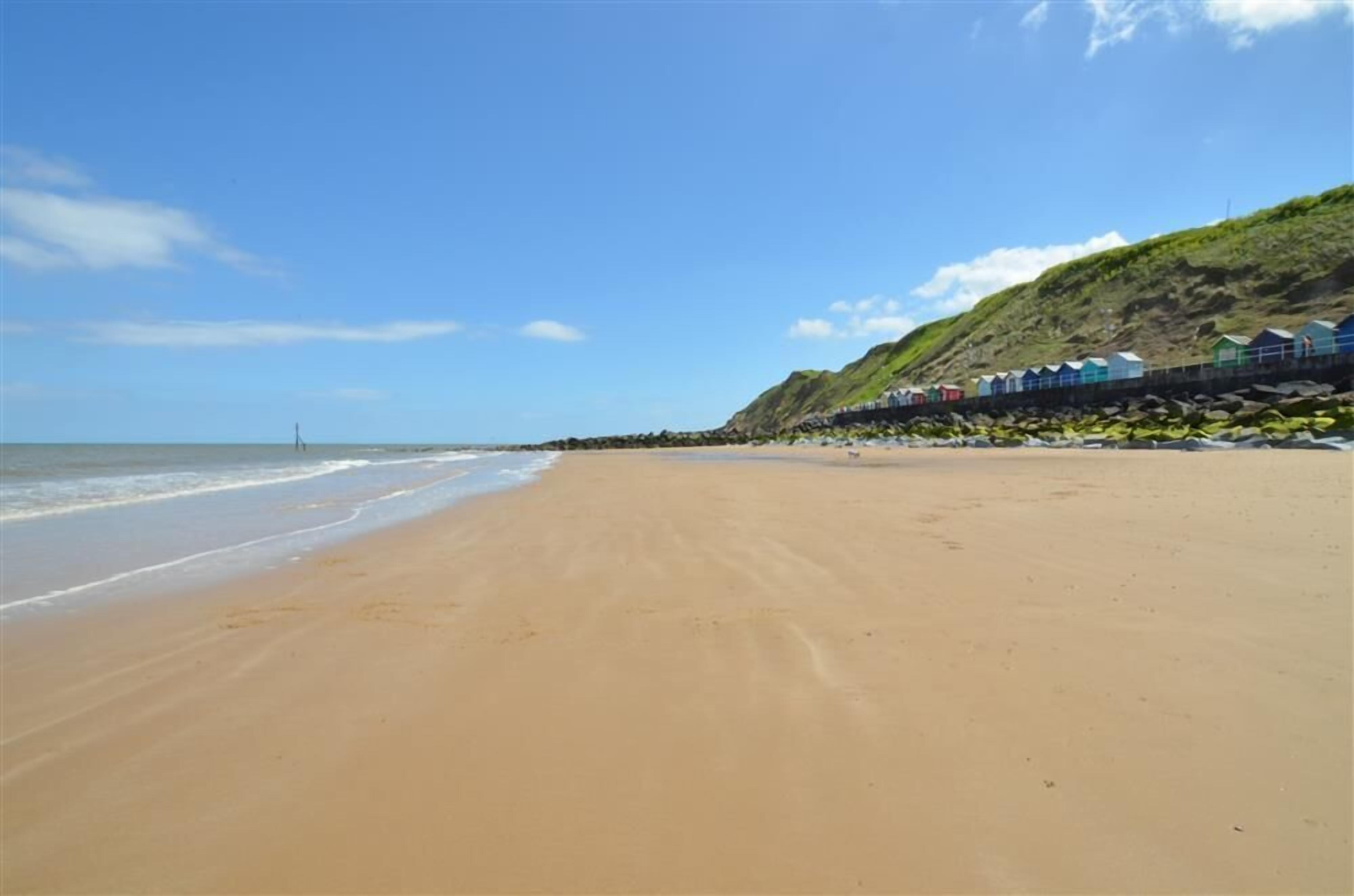A beach with a row of colorful beach huts along the shore.