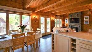 L’intérieur d’un chalet en bois comprend un coin repas, une cuisine et une cheminée.