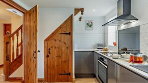 A modern kitchen with wooden doors, a built-in oven, and a stainless steel range hood. - 2 Bed in St. Issey (oc-w27345) (Tredinnick)