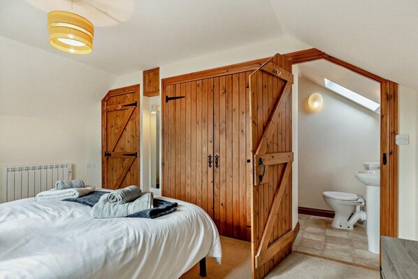 Ein Schlafzimmer mit einem Bett, einem Holzschrank und einem Badezimmer mit Toilette und Waschbecken.