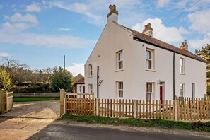 A two-story white house with a red door, a wooden fence, and a gravel driveway. - 3 Bed in Thurne (oc-t27347) (Ashby with Oby)