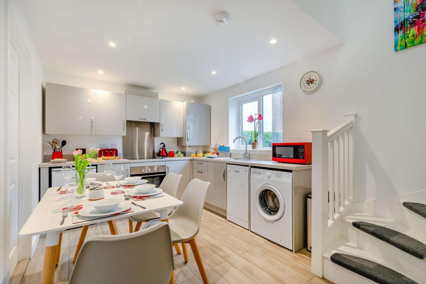 A modern kitchen with a dining area, built-in appliances, and a view of the outdoors.