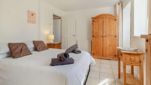 Ein Schlafzimmer mit Bett, einem Holzschrank, einem Nachttisch und einem Fenster.