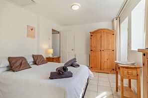 Une chambre à coucher avec un lit, une armoire en bois, une table de chevet et une fenêtre.