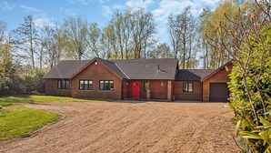 Ein zweistöckiges Holzhaus mit roter Tür, einem Schotterweg und einem umgebenden Garten.
