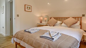 Een slaapkamer met een groot bed, twee nachtkastjes, een spiegel en een lijst met een afbeelding aan de muur.