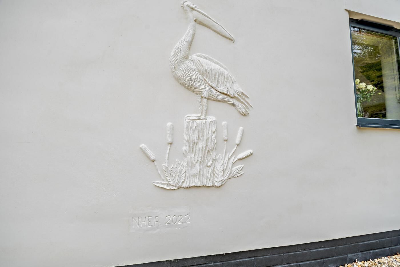 A wall relief of a bird on a rock, with the text 'NHEA 2022' below it.