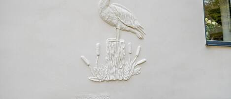A wall relief of a bird on a rock, with the text 'NHEA 2022' below it.