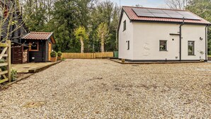 Een gebouw met een grindpad, een houten hek en een kleine schuur.