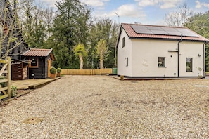 A building with a gravel driveway, a wooden fence, and a small shed.