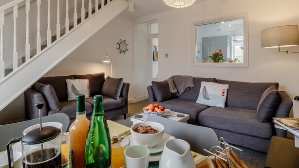A modern living room with a staircase, two sofas, a coffee table with breakfast items, and a large mirror. - 2 Bed in Southwold (oc-p27380) (Southwold)