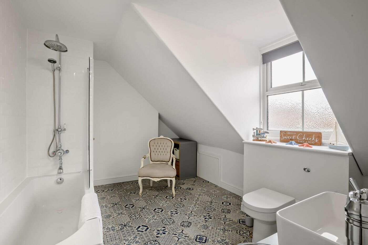 Een badkamer met douche, toilet en een stoel.