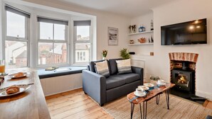 Una sala de estar moderna con un sofá, una mesa de centro, una chimenea y un televisor montado en la pared.
