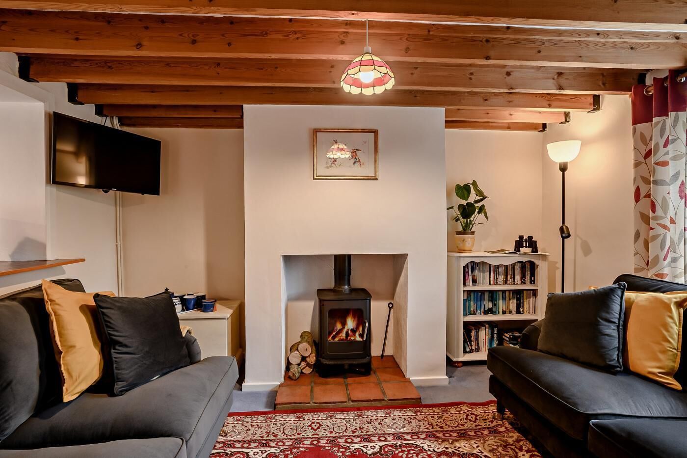 A cozy living room with a fireplace, sofas, a TV, and a bookshelf.