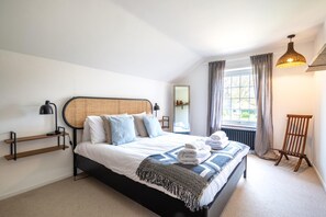 A bedroom with a bed, bedside lamps, a window with curtains, a radiator, and a chair. - 4 Bed in East Runton (oc-r27404) (East Runton)