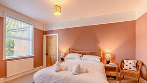Una camera da letto con un letto, lampade da comodino, una sedia, una finestra con tende e una porta.