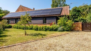 Een huis met schuin dak, zonnepanelen, een houten gevel en een grindpad.