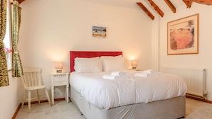 Een slaapkamer met een groot bed, twee nachtkastjes, een stoel en een schilderij aan de muur.