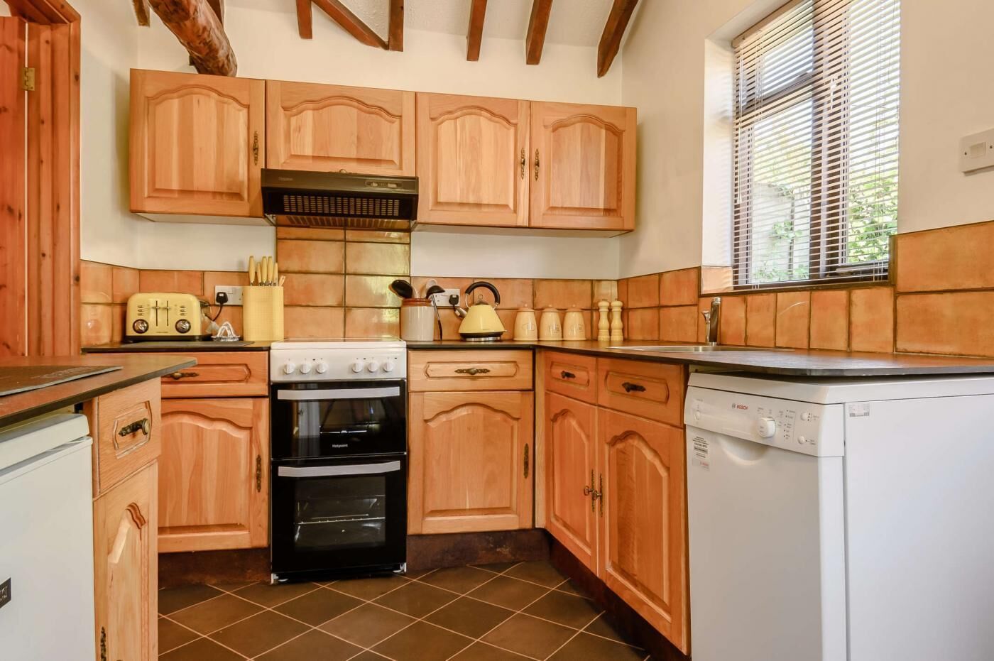 Una cocina con armarios de madera, estufa, horno y lavavajillas.